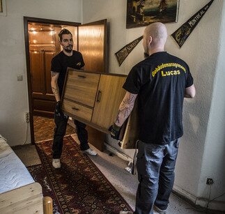 Zwei Mitarbeiter tragen ein Möbelstück bei einer Beräumung